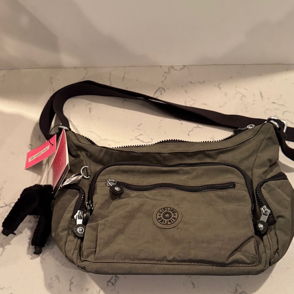 Kipling  Ross post bag in “Moss” with black zippers and trim.